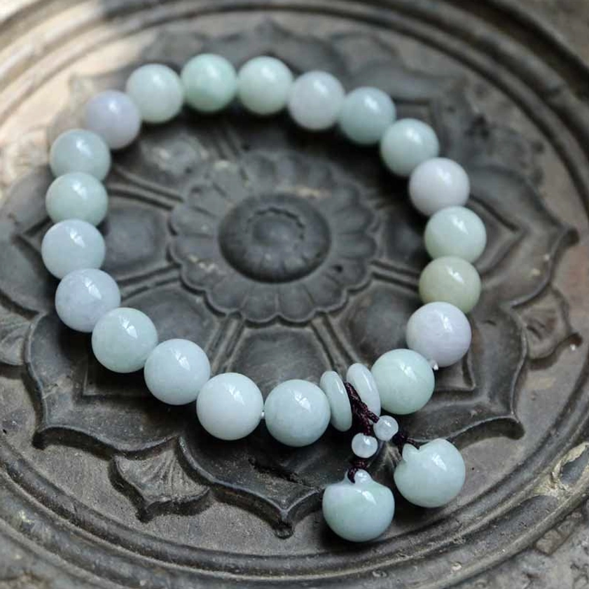 Premium handcrafted jade bracelet with uniform light green natural jade beads and single round jade gourd pendant on carved stone decorative tray