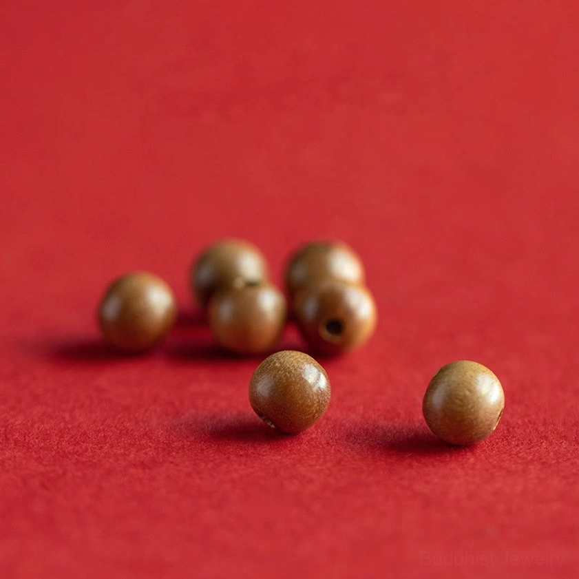 Loose natural peach wood beads in smooth matte finish on red background