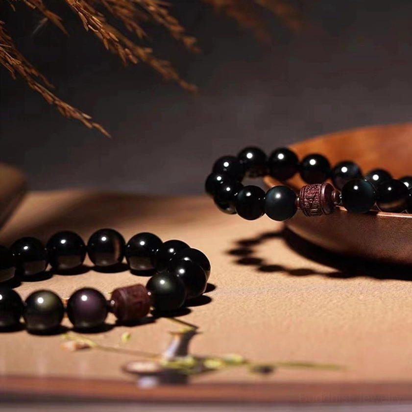 Natural polished obsidian beads showing glossy finish with subtle golden and rainbow iridescence