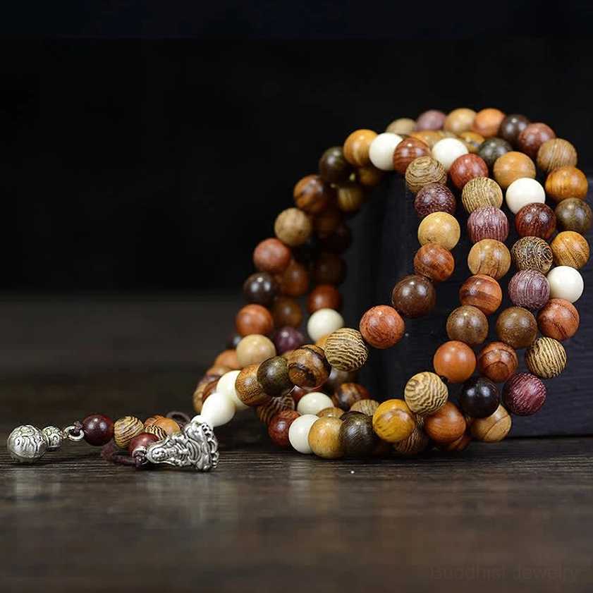 Buddhist prayer mala with curved beaded strands featuring silver ornaments and varied natural wood grain colors, overhead close-up