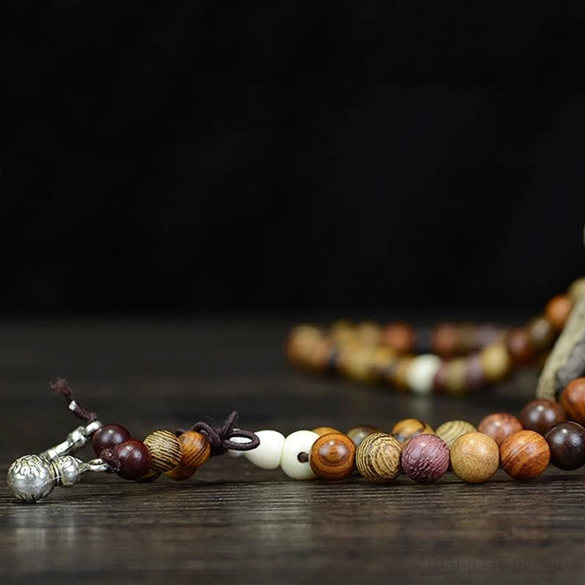 Detailed natural wood mala prayer beads strands with silver pendants on dark wooden surface, close-up side view