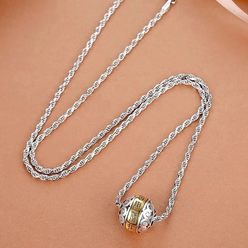 Buddhist mantra necklace flat lay overhead view with twisted rope chain and spherical two-tone copper pendant on brown background