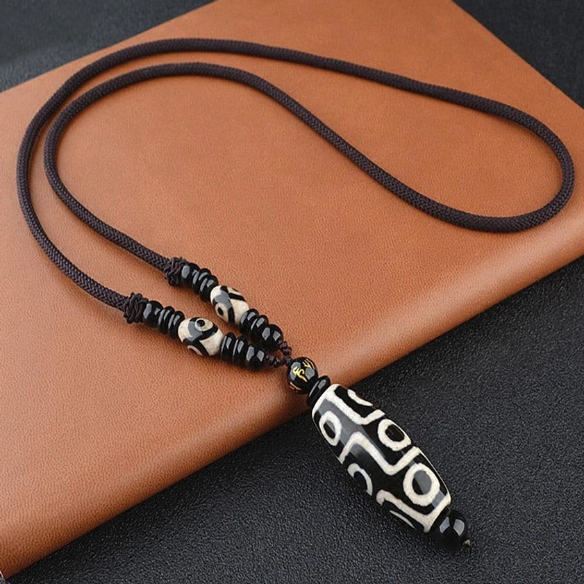 Nine-eye dzi bead necklace with black onyx and sacred mantra cord detail showcasing traditional Buddhist craftsmanship