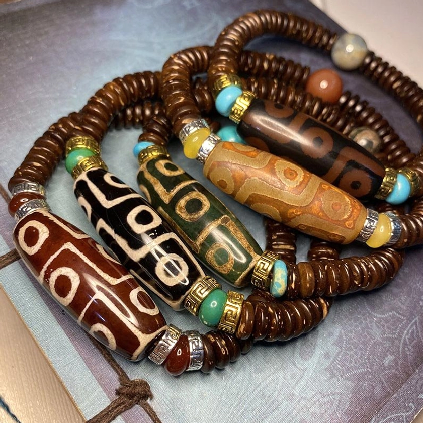collection of handmade nine-eye dzi bead bracelets in multiple colors featuring agate beads with traditional eye patterns and natural gemstone accents