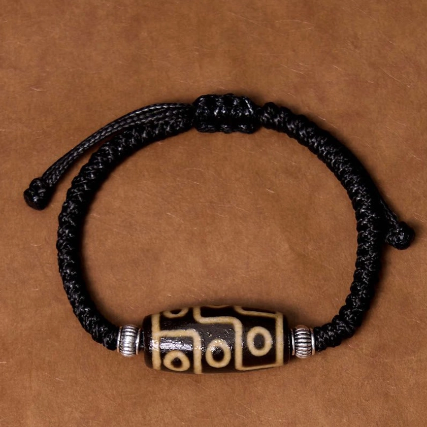 Nine-eye dzi bead bracelet complete circular view on brown leather background showing full symmetrical layout