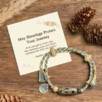 Nine-eye dzi bead bracelet with gift message card displayed on wooden surface with natural elements