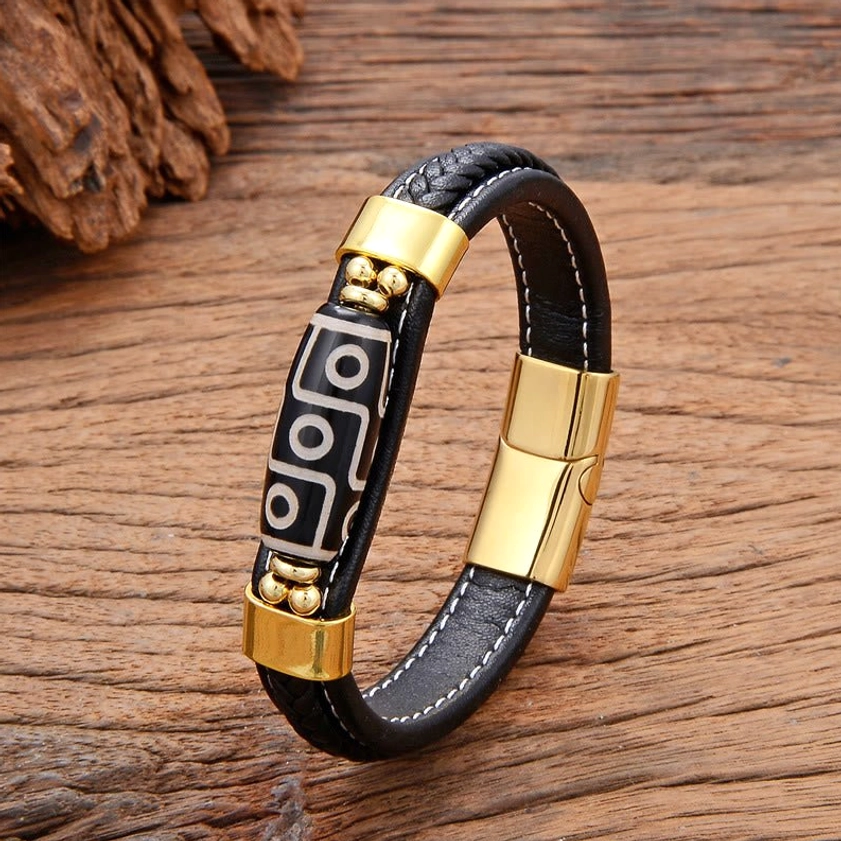 Gold-tone Nine-Eye Dzi bead leather bracelet with premium buckle closure and decorative metal accents on pine wood background