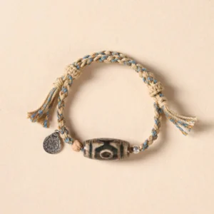 Nine-eye dzi bead bracelet with beige and light blue braided rope and metal pendant charm