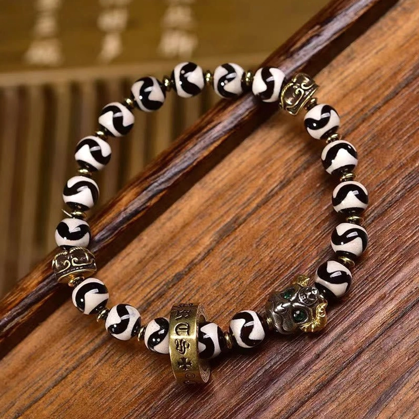 Authentic Nine-Eye Dzi Bead Buddhist Bracelet with Hand-Painted Wave Patterns and Copper Metal Accents on Wooden Surface