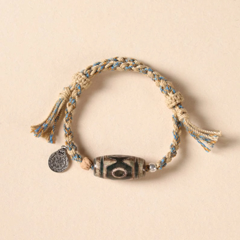 Nine-eye dzi bead bracelet with beige and light blue braided rope and metal pendant charm
