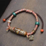 Nine-eye dzi bead Buddhist protection bracelet with mixed braided rope, decorative beads and metal Buddha pendant in overhead flat lay