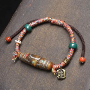 Nine-eye dzi bead Buddhist protection bracelet with mixed braided rope, decorative beads and metal Buddha pendant in overhead flat lay
