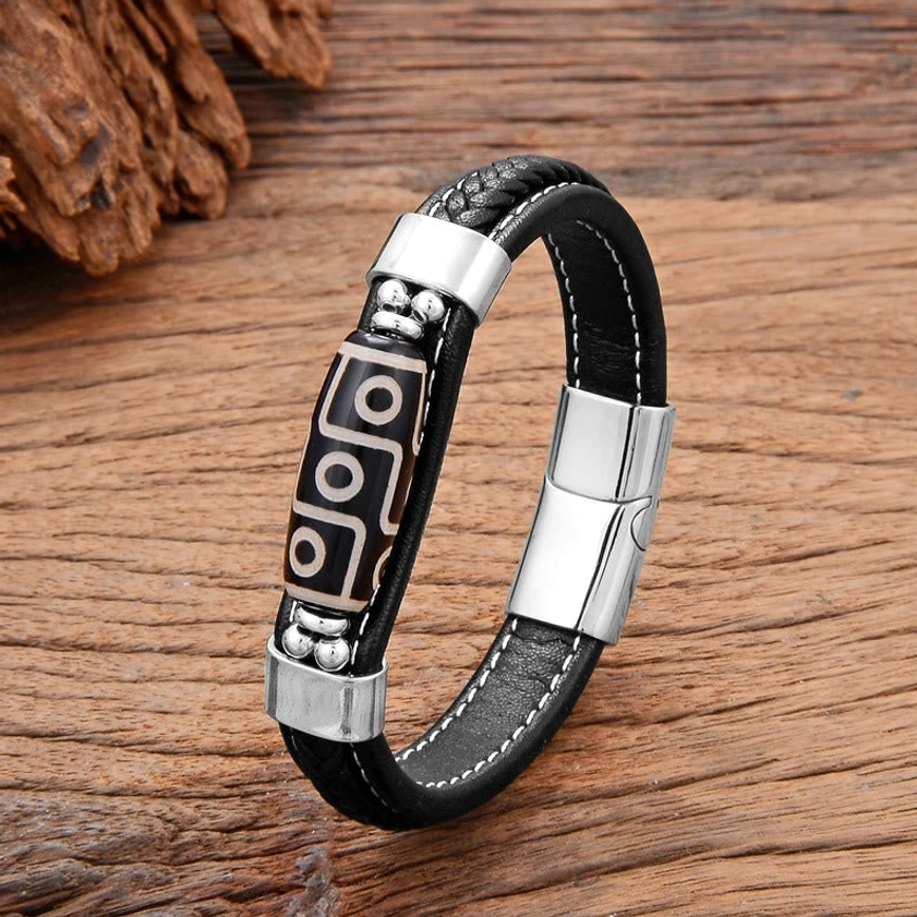 Silver-tone Nine-Eye Dzi bead leather bracelet with stainless steel buckle and decorative silver bead details on wooden surface