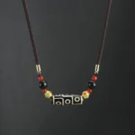 Nine-Eye Dzi Bead Buddhist necklace pendant in black and white natural agate with adjustable woven cord and gold metal accents, front flat view