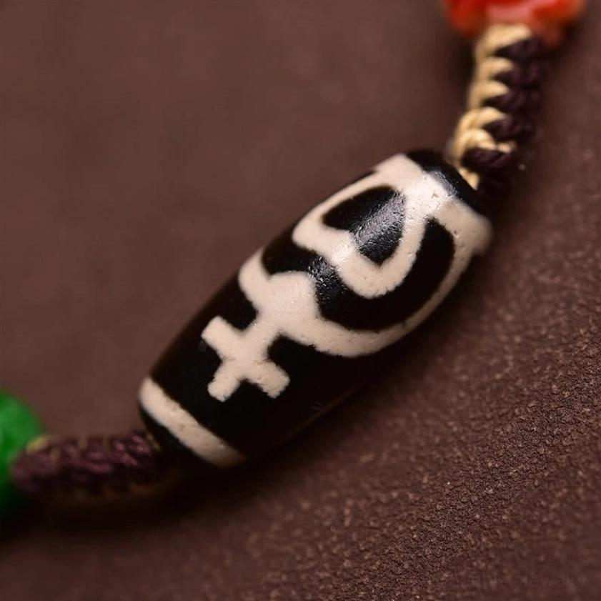 Close-up macro detail of nine-eye dzi bead showing black-white hand-painted pattern and premium braided rope construction