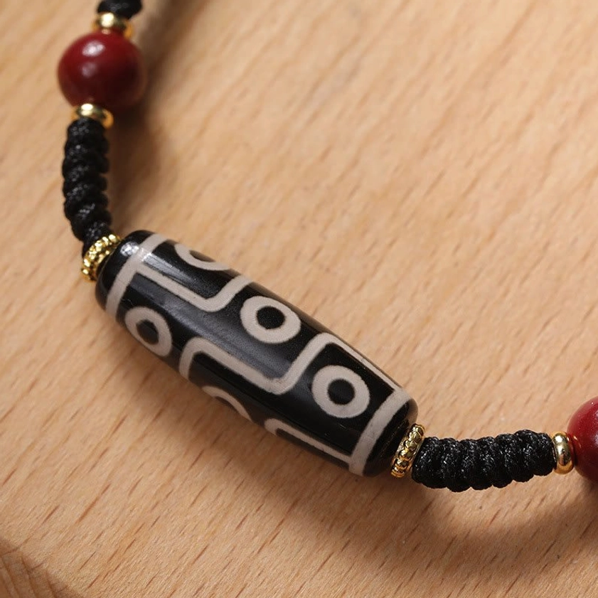 Close-up of authentic nine-eye Dzi bead showing intricate black and white pattern with gold metal spacers