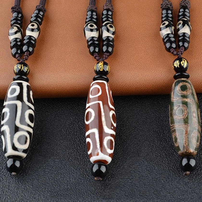 Nine-eye dzi bead wealth protection necklace close-up showing hand-painted sacred eye symbols and natural stone detail