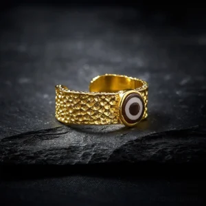 Nine-eye dzi bead adjustable copper brass ring, open cuff design with hammered texture, front angled view on stone surface