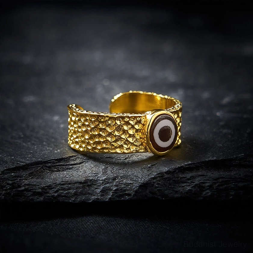 Nine-eye dzi bead adjustable copper brass ring, open cuff design with hammered texture, front angled view on stone surface