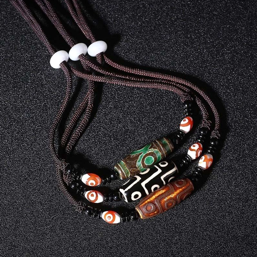 Buddhist nine-eye dzi bead amulet necklace close-up detail of carved stone pattern and protective symbolism