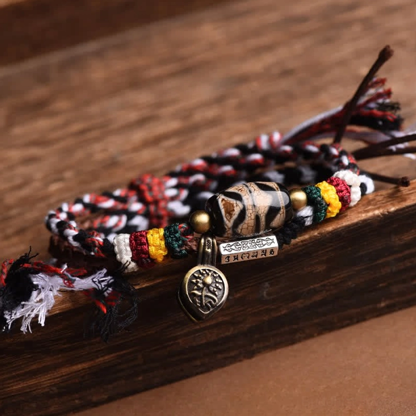 Nine-eye dzi bead Buddhist bracelet detail showing hand-painted bead and braided rope construction