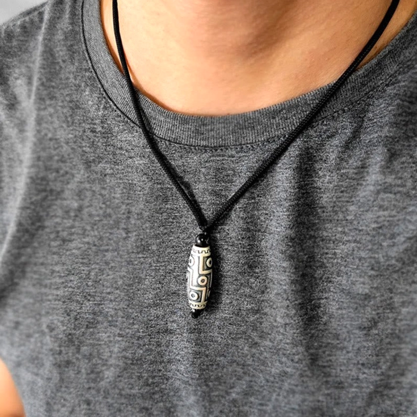 Nine-eye dzi necklace worn on chest showing how the spiritual pendant sits near the heart chakra