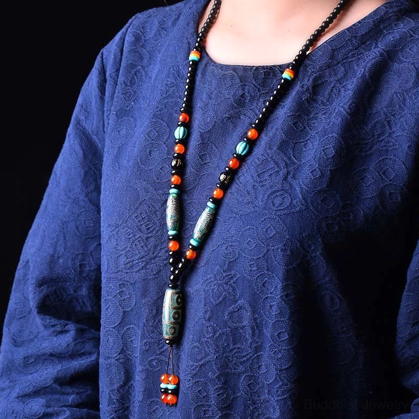 Woman wearing nine-eye Dzi bead Buddhist necklace pendant showing actual wearing effect on body, demonstrating how the mantra necklace looks when worn with blue textured clothing