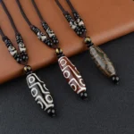 Collection of assorted nine-eye dzi bead necklaces in multiple colors displaying black, red, and green Buddhist amulet beads on braided cords