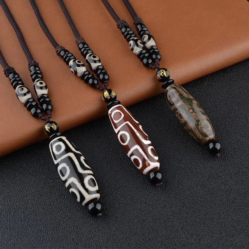 Collection of assorted nine-eye dzi bead necklaces in multiple colors displaying black, red, and green Buddhist amulet beads on braided cords
