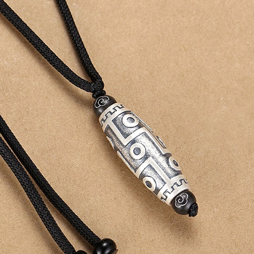 Buddhist dzi bead pendant side angle displaying detailed geometric engravings and celestial symbols