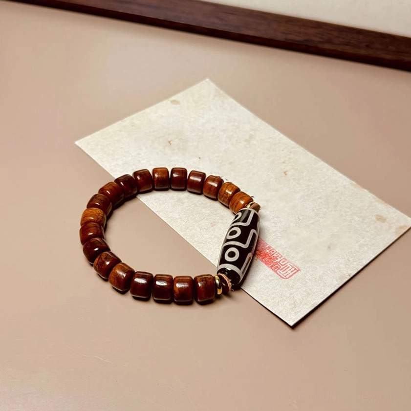 Handmade nine-eye dzi protection bracelet on beige paper surface highlighting reddish-brown bone bead texture