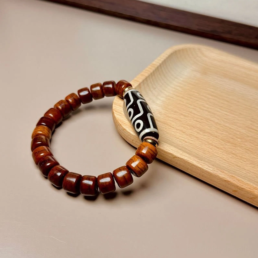 Buddhist nine-eye dzi bone beaded bracelet minimalist flat lay with natural light wooden background