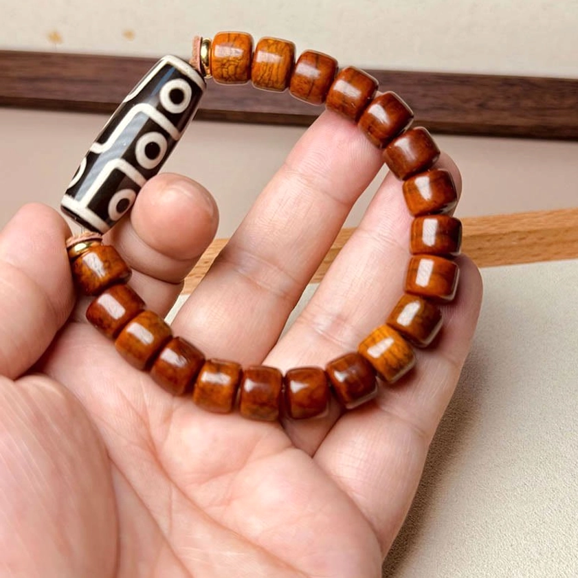 Nine-eye dzi Buddhist bracelet close-up in human palm showing wearable size and bead arrangement