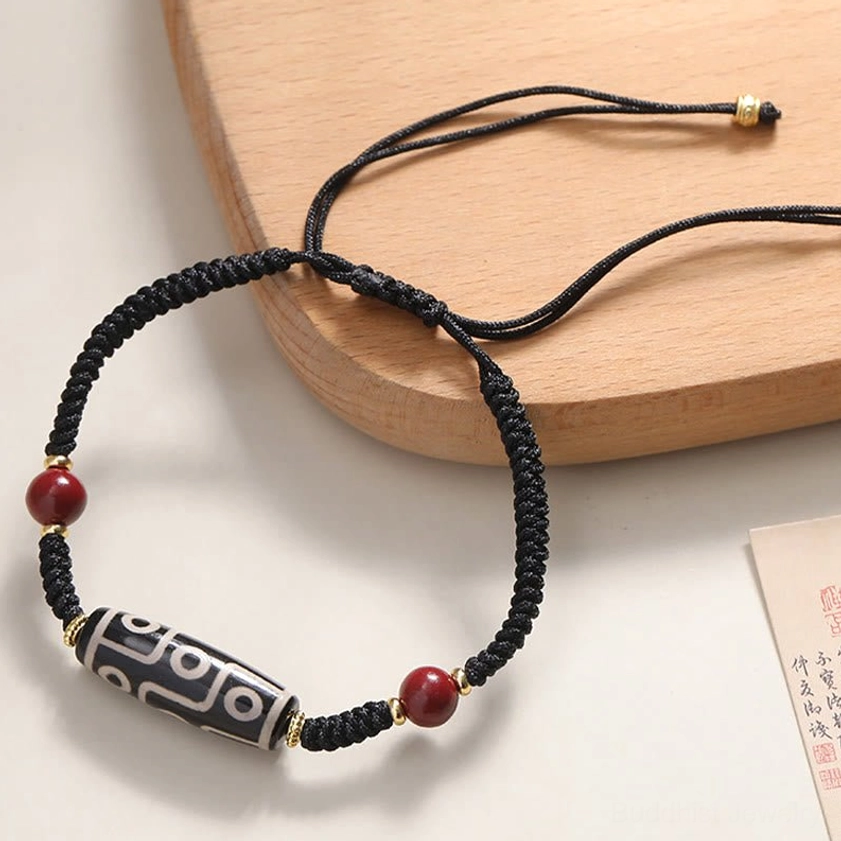 Handcrafted nine-eye Dzi bead bracelet with adjustable black cord and red cinnabar accents - side view