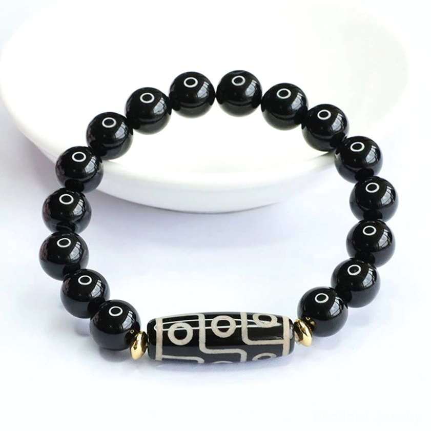 Nine-eye dzi black onyx Buddhist bracelet with high-gloss polished beads and dzi charm on ceramic plate background