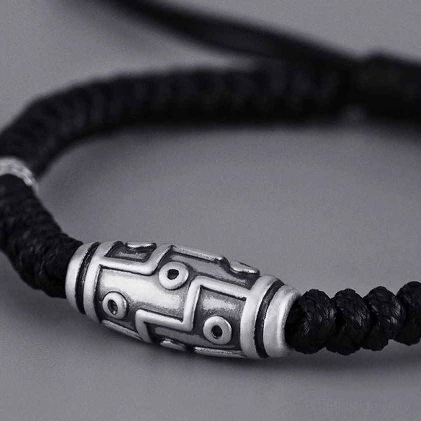 Close-up side view of sterling silver nine-eye dzi bead bracelet highlighting detailed dzi eye pattern and braided black rope