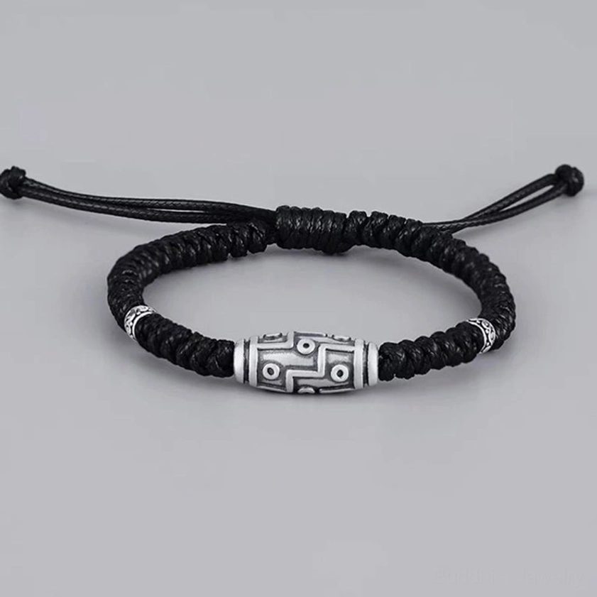 Full overhead flat lay of adjustable nine-eye dzi silver bracelet showing complete design with drawstring ends and black-silver color scheme
