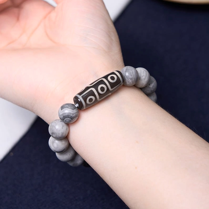 Buddhist nine-eye dzi bracelet on wrist with matte gray picasso jasper beads and sacred dzi charm pendant