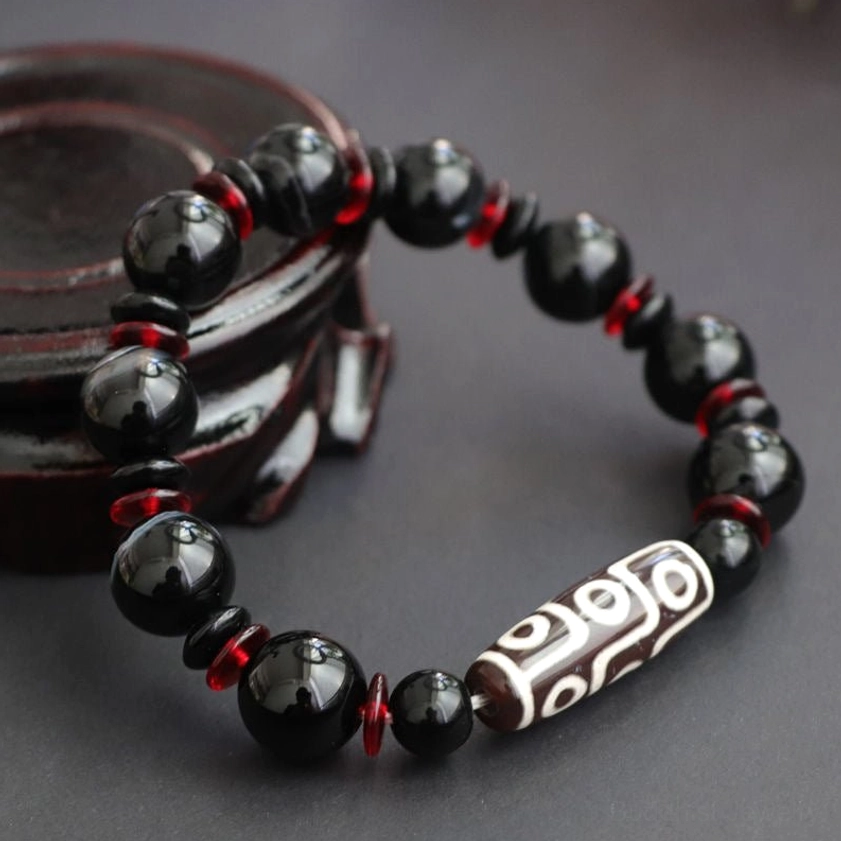 Nine-Eye Dzi Bead Black Onyx Bracelet overhead view on wooden display stand