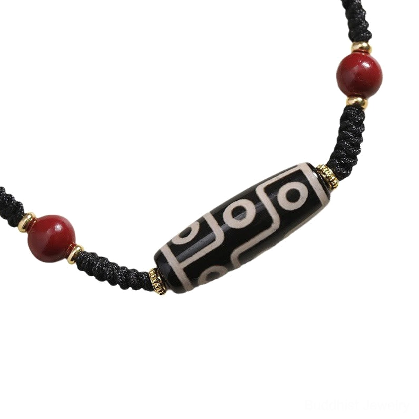 Symmetrical view of nine-eye Dzi bead bracelet with red beads, gold spacers, and polished dzi bead centerpiece