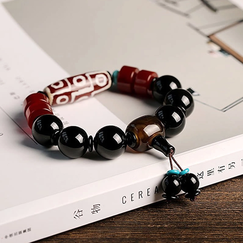 Handcrafted nine-eye dzi black onyx wealth protection bracelet on vintage book and wooden surface