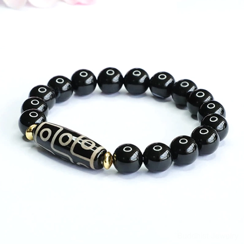 Direct overhead view of nine-eye dzi black onyx Buddhist bracelet with elastic cord on clean white background