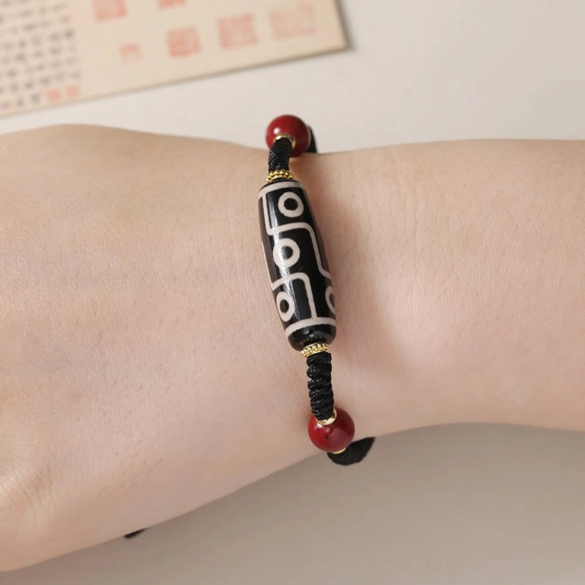 Nine-eye Dzi bead bracelet worn on wrist showing comfortable fit with red cinnabar beads and adjustable strap