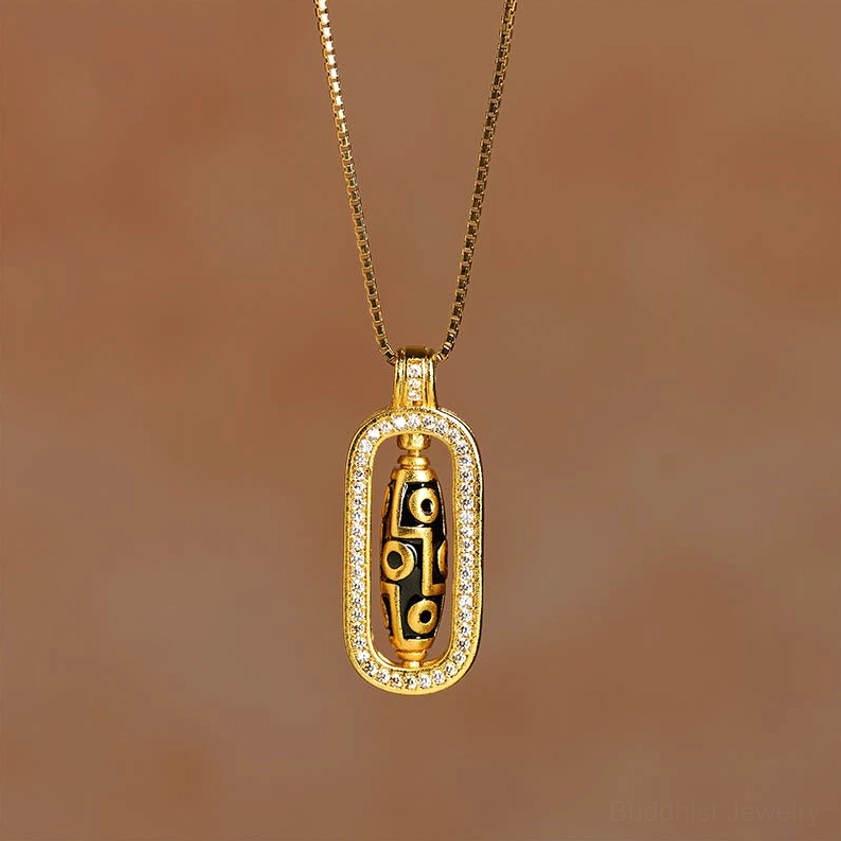 Gold nine-eye dzi pendant necklace with thin box chain and rotatable dzi charm photographed in upright position