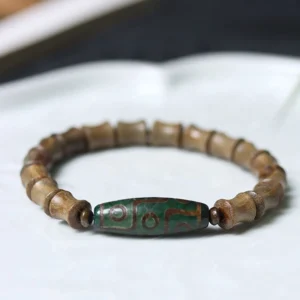 Nine-eye dzi green sandalwood Buddhist bracelet overhead flat lay view on white ceramic tray