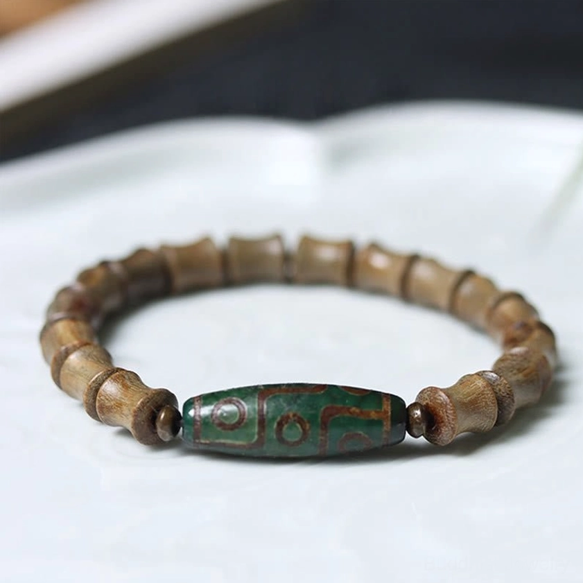 Nine-eye dzi green sandalwood Buddhist bracelet overhead flat lay view on white ceramic tray