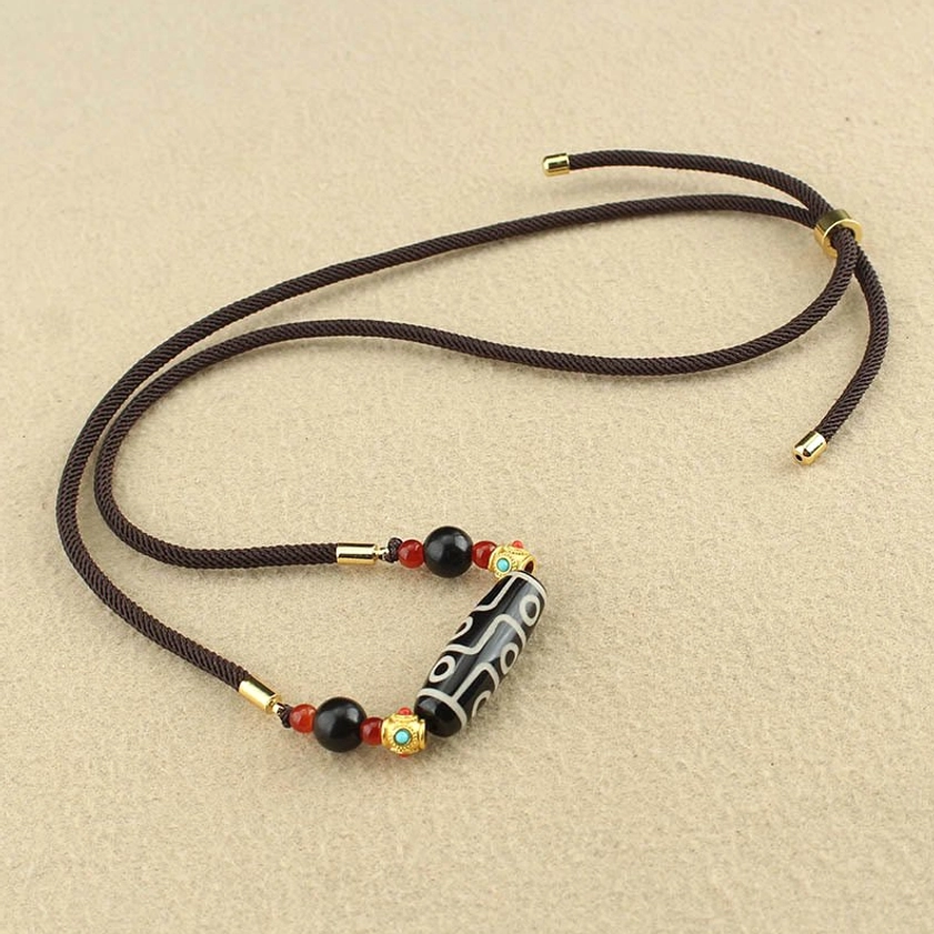 Nine-Eye Dzi Buddhist necklace pendant flat lay showing full adjustable cord length and compact accessory set
