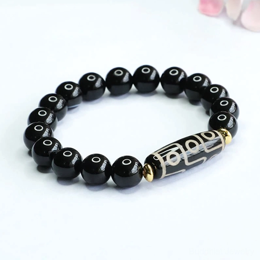 Front view of nine-eye dzi bead onyx bracelet with dzi positioned on right side against pure white backdrop