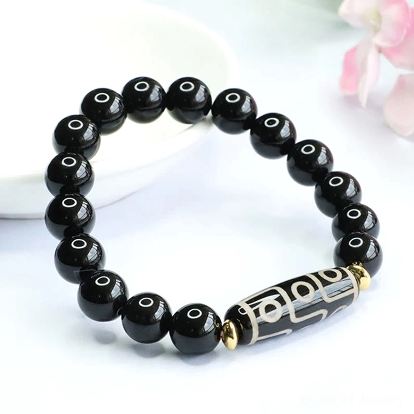 Side view of nine-eye dzi bead protection bracelet showing polished black onyx beads and traditional dzi charm design