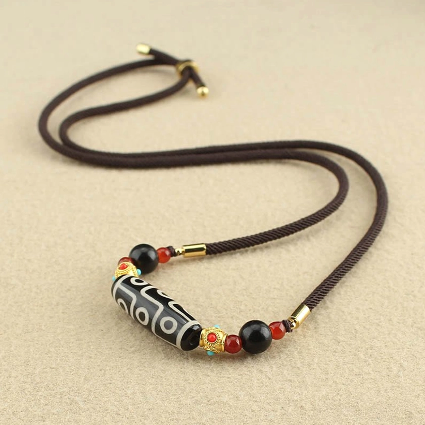 Nine-Eye Dzi Bead Buddhist necklace pendant with adjustable toggle clasp and dark brown woven rope on light background